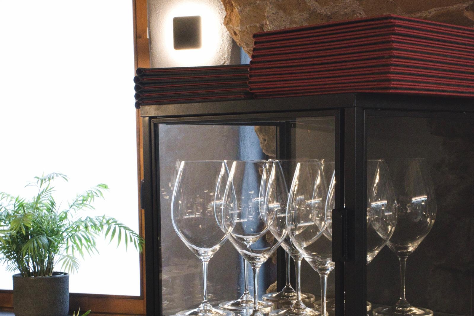 Copas de vino y cartas en la vitrina de Casa Maestro Bistró, preparadas para el servicio